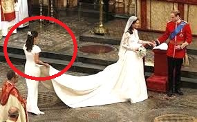 a maid of honour holding the bride's dress at a royal wedding