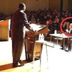 a moderator conducting a debate sitting before twp participates