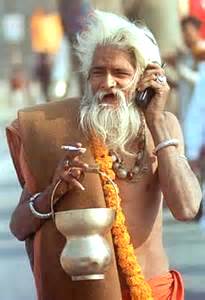a modern day sadhu with a cigarette in one hand and a cell phone in the other